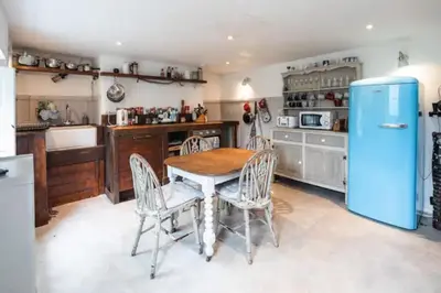a kitchen with a table and a blue refrigerator at Charming Cottage near Beach! in Redruth