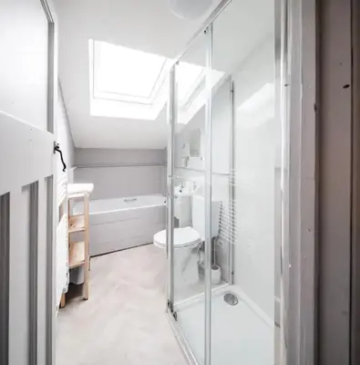 a white bathroom with a shower and a toilet at Charming Cottage near Beach! in Redruth