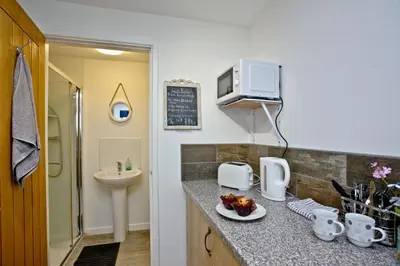 a kitchen with a sink and a counter with a plate of food at Wheal Tor - Free WiFi - Parking - Pet Friendly - On-site Activities in Helston