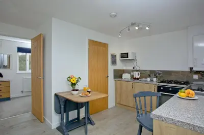 a kitchen with a table and a counter top at Wheal Tor - Free WiFi - Parking - Pet Friendly - On-site Activities in Helston