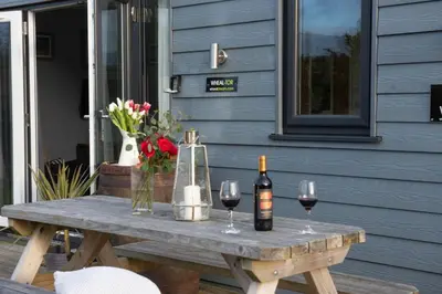 a picnic table with two bottles and two glasses of wine at Wheal Tor - Free WiFi - Parking - Pet Friendly - On-site Activities in Helston