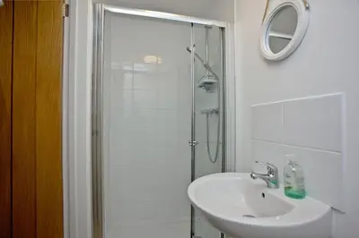 a white bathroom with a sink and a shower at Wheal Tor - Free WiFi - Parking - Pet Friendly - On-site Activities in Helston