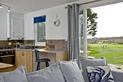 a kitchen and living room with a couch and a table at Wheal Tor - Free WiFi - Parking - Pet Friendly - On-site Activities in Helston