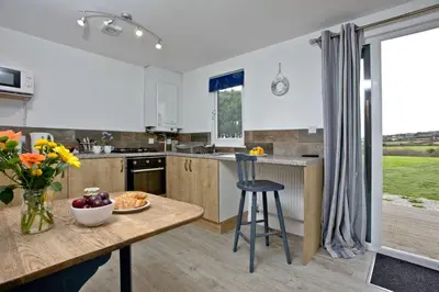 a kitchen with a table with a bowl of fruit on it at Wheal Tor - Free WiFi - Parking - Pet Friendly - On-site Activities in Helston