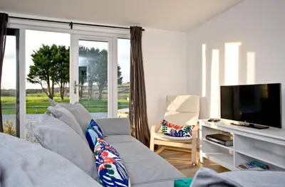 a living room with a gray couch and a television at Wheal Amelia - Free WiFi - Parking - Pet Friendly - On-site Activities in Helston