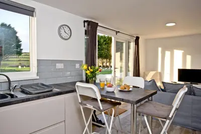 a kitchen and living room with a table and chairs at Wheal Amelia - Free WiFi - Parking - Pet Friendly - On-site Activities in Helston