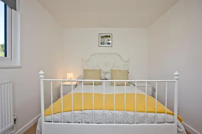 a white crib in a white room with a bed at Wheal Amelia - Free WiFi - Parking - Pet Friendly - On-site Activities in Helston
