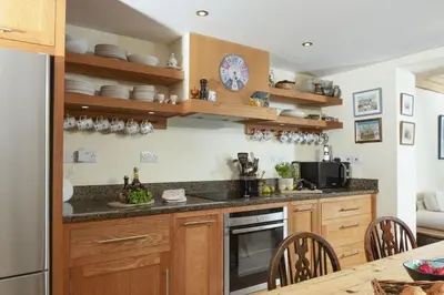a kitchen with wooden cabinets and a counter top at Deugh an Chy in Carleen
