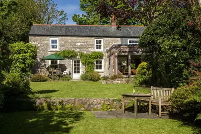 a stone house with a table in the yard at Deugh an Chy in Carleen