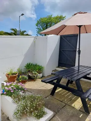 a wooden picnic table with an umbrella and flowers at Porthmeor Beach 150 m Parking 2-3 cars in St Ives