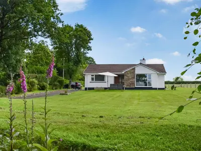 a white house with a large grass yard at Trelawney Bungalow in Callington