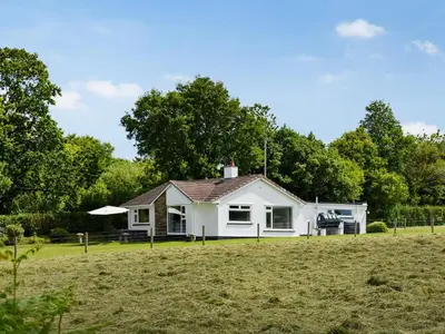 a white house on a field with trees at Trelawney Bungalow in Callington