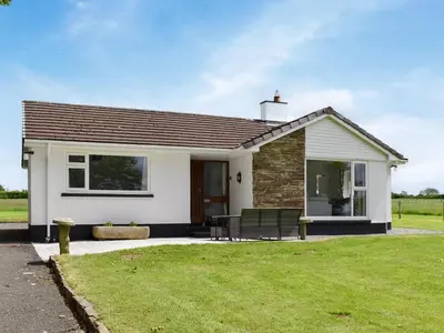 a white house with a lawn in front of it at Trelawney Bungalow in Callington