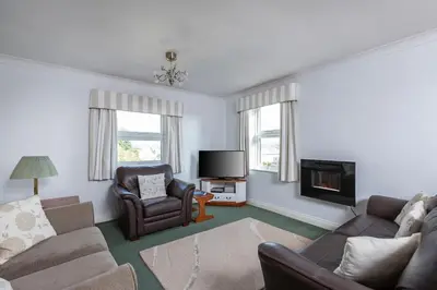 a living room with a couch and a chair and a television at Fabulous High Street Townhouse With Stunning Views & Parking at 'Eagles Nest' in Falmouth