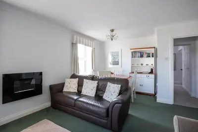 a living room with a leather couch and a kitchen at Fabulous High Street Townhouse With Stunning Views & Parking at 'Eagles Nest' in Falmouth