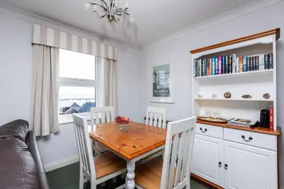 a dining room with a wooden table and chairs at Fabulous High Street Townhouse With Stunning Views & Parking at 'Eagles Nest' in Falmouth