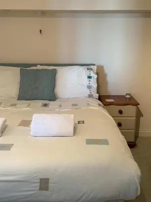 a large white bed with a white towel on it at Fabulous High Street Townhouse With Stunning Views & Parking at 'Eagles Nest' in Falmouth