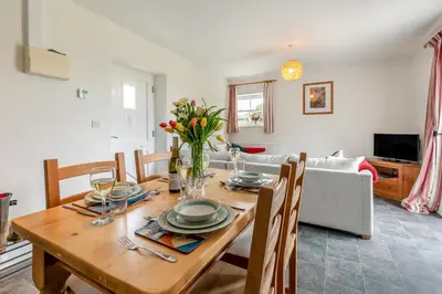 a dining room with a wooden table with flowers on it at 2 Bed in Ponsanooth oc-f28845 in Ponsanooth