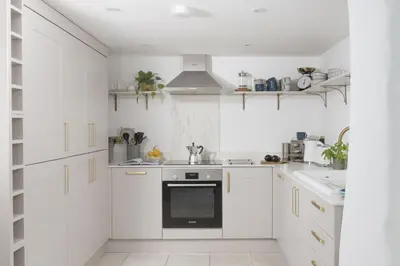 a kitchen with white cabinets and a black oven at 11 Tywarnhayle House, Perranporth in Perranporth