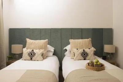 a bedroom with two beds and a green headboard at 11 Tywarnhayle House, Perranporth in Perranporth