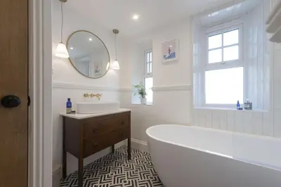 a bathroom with a tub and a sink and a mirror at 11 Tywarnhayle House, Perranporth in Perranporth