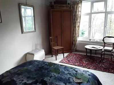a bedroom with a bed and chairs and a window at Halcyon Days in Kenwyn