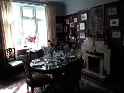 a dining room with a table and a fireplace at Halcyon Days in Kenwyn