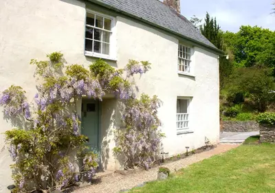 a white house with a wreath of purple flowers at The Old Barn at Bosillion House in Grampound