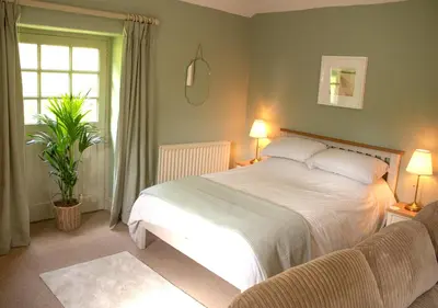 a bedroom with a white bed and a window at The Old Barn at Bosillion House in Grampound