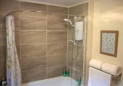a bathroom with a shower with a bath tub at The Old Barn at Bosillion House in Grampound