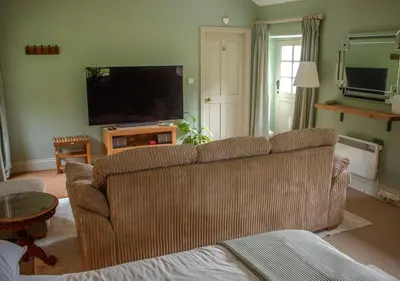 a living room with a couch and a flat screen tv at The Old Barn at Bosillion House in Grampound