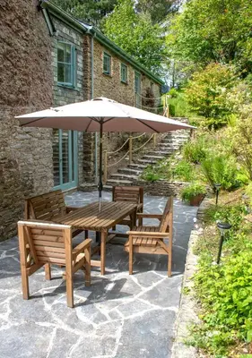 a wooden table with two chairs and an umbrella at The Old Barn at Bosillion House in Grampound
