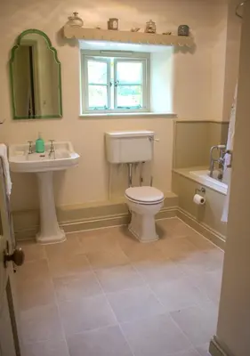 a bathroom with a toilet and a sink and a window at The Old Barn at Bosillion House in Grampound