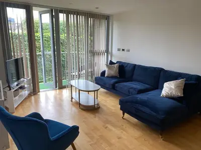 a living room with a blue couch and a table at Modern apartment, Fistral beach in Newquay