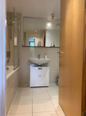 a bathroom with a sink and a shower and a mirror at Modern apartment, Fistral beach in Newquay