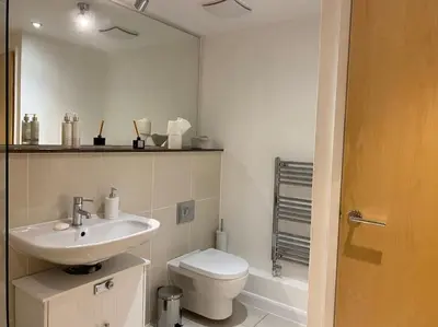 a white bathroom with a toilet and a sink at Modern apartment, Fistral beach in Newquay