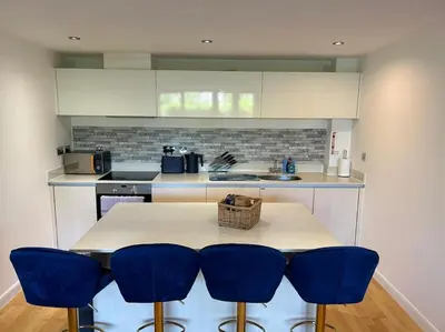 a kitchen with a table with four blue chairs at Modern apartment, Fistral beach in Newquay