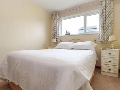 a bedroom with a white bed and a window at Skylarks! in St. Agnes