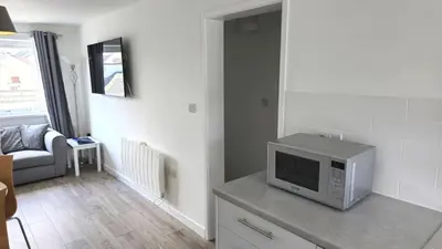 a living room with a television on a counter at 5 Penhale in Perranporth