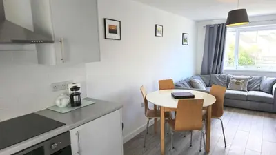 a kitchen and living room with a table and a couch at 5 Penhale in Perranporth