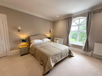 a bedroom with a bed and a large window at Moorswater Lodge Country House with Wine Bar in Liskeard