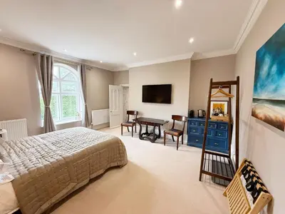 a bedroom with a bed and a desk in it at Moorswater Lodge Country House with Wine Bar in Liskeard