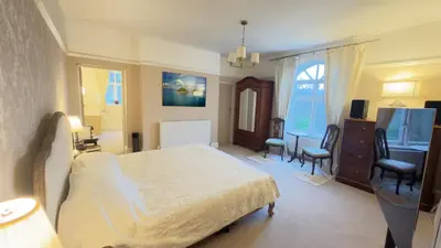 a bedroom with a bed and a desk and chairs at Moorswater Lodge Country House with Wine Bar in Liskeard