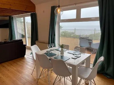 a dining room with a table and chairs and a large window at House with stunning sea views in Downderry