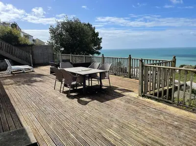 a table and chairs on a deck overlooking the ocean at House with stunning sea views in Downderry