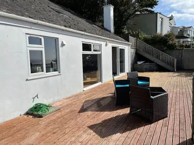a patio with two chairs and a table and a house at House with stunning sea views in Downderry