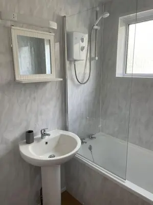 a white bathroom with a sink and a shower at House with stunning sea views in Downderry