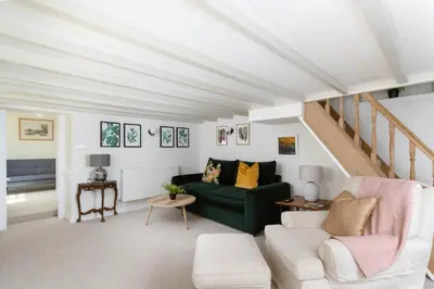 a living room with a green couch and a staircase at 4-Bed Cottage - Pets with Garden & Wood Burner in Helston