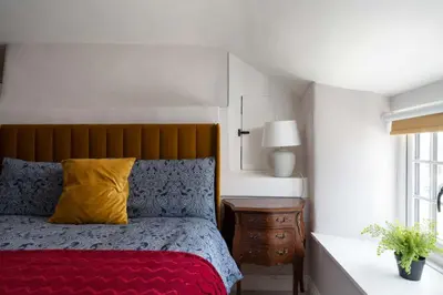a bedroom with a bed with a yellow pillow at 4-Bed Cottage - Pets with Garden & Wood Burner in Helston