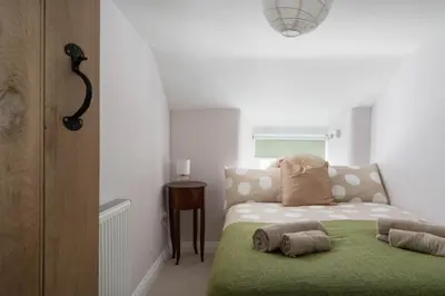 a small bedroom with a bed and a small table at 4-Bed Cottage - Pets with Garden & Wood Burner in Helston